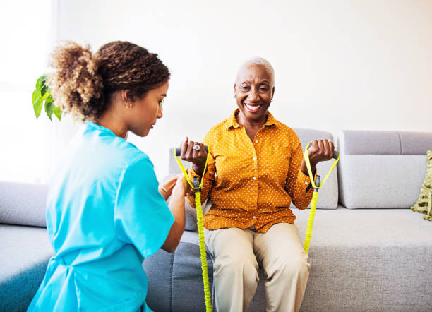 Nurse home visiting a patient, showing her exercises for arms strenght